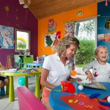 Une femme et une enfant dans une salle d'activités colorée à Camping Les Iles.