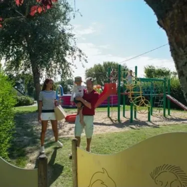 Une famille au parc infantile à Camping Les Iles.