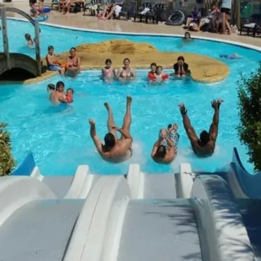 Camping Les Iles - personnes sautant dans une piscine avec toboggan