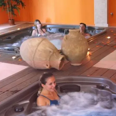 Camping Le Galoubet : piscine intérieure avec jacuzzis et vases en terre cuite.