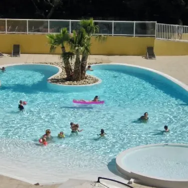 Piscine avec enfants nageant et flottant dans une zone détente au Camping Le Galoubet