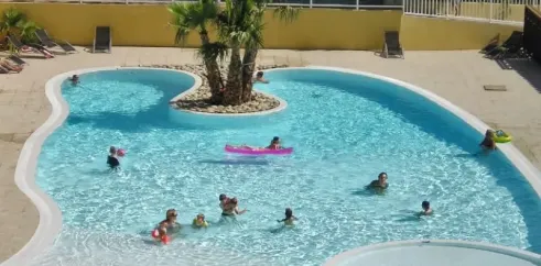 Piscine avec enfants nageant et flottant dans une zone détente au Camping Le Galoubet