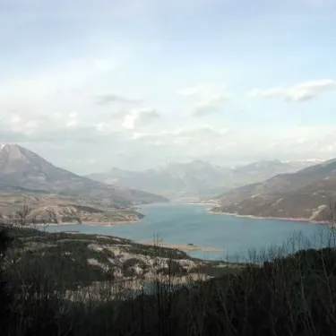 Vue panoramique du lac entouré de montagnes enneigées depuis un point élevé.