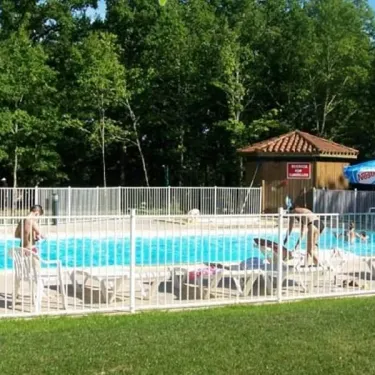 Piscine entourée de chaises longues et d'une cabane au Camping Lac aux Oiseaux