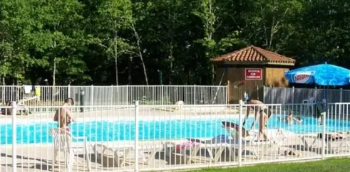 Piscine entourée de chaises longues et d'une cabane au Camping Lac aux Oiseaux