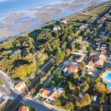 Vue aérienne du Camping Village Corsaire avec piscine et mobil-homes près de la mer.