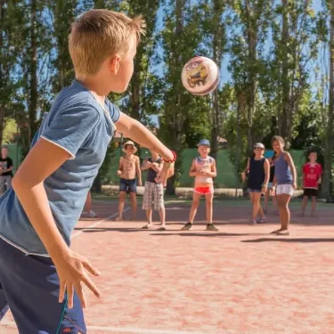 Enfant joue au ballon dans le parc du Camping Le Lamparo
