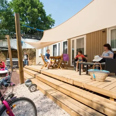 Camping Domaine de Verdagne : mobil-home avec terrasse en bois et enfants jouant.