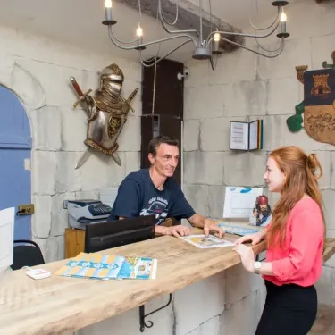 Reception du camping avec employé et cliente en train de discuter.