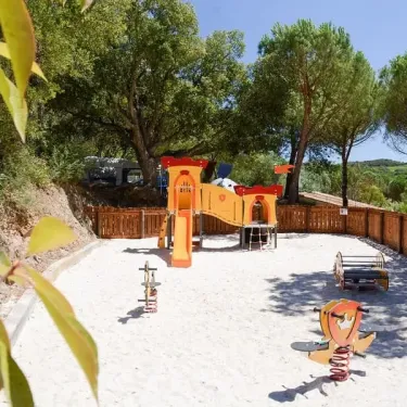 Parc d'attractions pour enfants avec toboggan, balançoire et structures colorées.