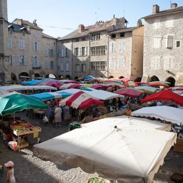 Marché animé sous des parasols colorés dans une place pavée, Camping Hameau Saint Martial