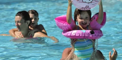 Enfant dans une piscine avec un ballon Hello Kitty et des flottants roses à Camping Les Ondines
