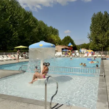 Piscine entourée d'arbres, fontaine centrale, enfants jouant, Camping Les Ondines