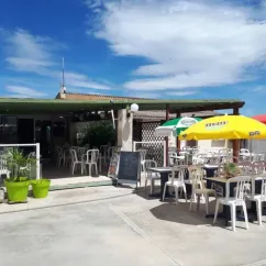 Camping Borepo : terrasse avec parasols jaune et rouge et chaises blanches
