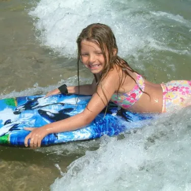 Enfant sur planche à voile au bord de l'eau au Camping La Plage