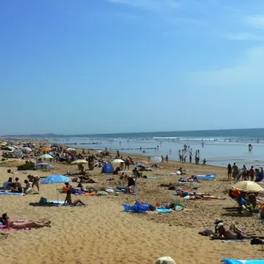 Plage animée avec des visiteurs sous parasols au Camping La Plage