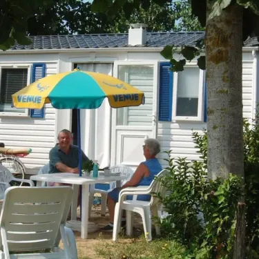 Camping La Plage : deux personnes assises à table sous un parasol