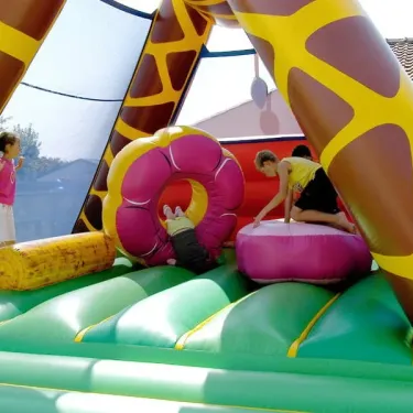 Enfants jouant dans une aire gonflable girafe au Camping La Plage