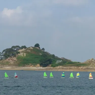 Voiliers colorés sur l'eau près d'une île verdoyante au Camping Baie de Terenez