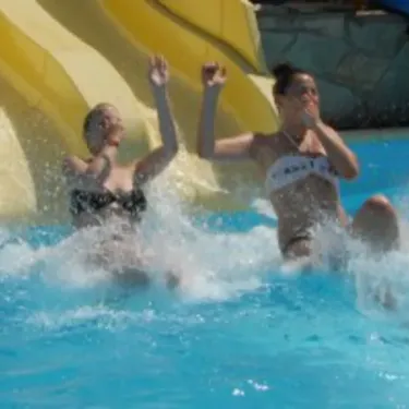 Deux femmes s'amusent dans une chute d'eau à l'aquapark du Camping Du Kérou