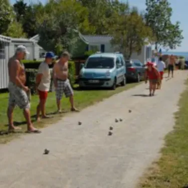 Camping Du Kérou : groupe de personnes jouant au billard sur une allée entre des caravanes.