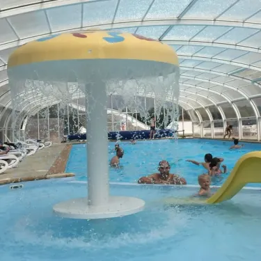 Piscine intérieure avec fontaine et toboggan jaune au Camping Du Golf