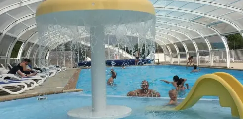 Piscine intérieure avec fontaine et toboggan jaune au Camping Du Golf