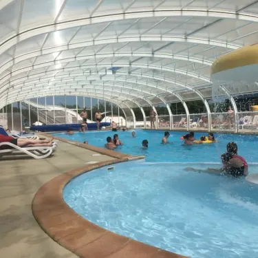 Piscine couverte avec enfants nageant et adultes détendant Camping Du Golf