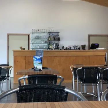 Bar avec tabouret en bois et verres alignés au Camping Du Golf
