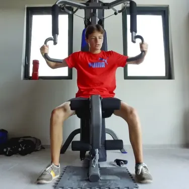 Jeune garçon faisant du fitness sur un appareil de musculation dans une salle équipée