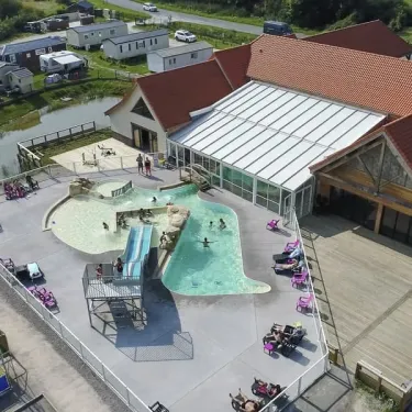Vue aérienne du camping avec piscine, toboggan et mobil-homes près d'un étang