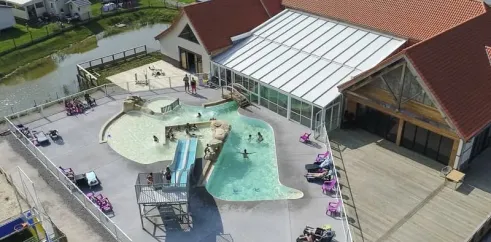 Vue aérienne du camping avec piscine, toboggan et mobil-homes près d'un étang