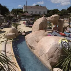Camping La Boutinardière : bassin naturel entouré de rochers et d'arbustes