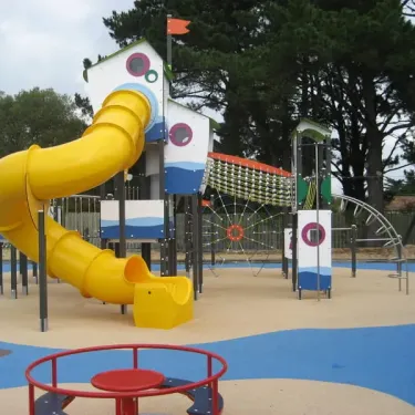 Parc d'attractions pour enfants avec toboggan jaune et structures colorées au Camping La Boutinardière