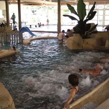 Piscine intérieure avec toboggan et personnes nageant au Camping La Boutinardière
