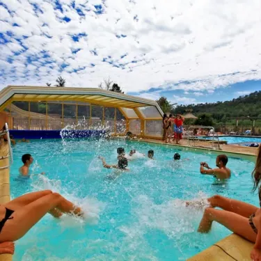Piscine extérieure du Camping Des Chênes Verts avec des enfants qui jouent dans l'eau.
