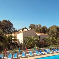 Pool avec chaises longues bleues et palmiers près d'une villa au Camping Résidence Thalassa