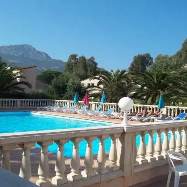 Piscine entourée de palmiers et de chaises longues au Camping Résidence Thalassa