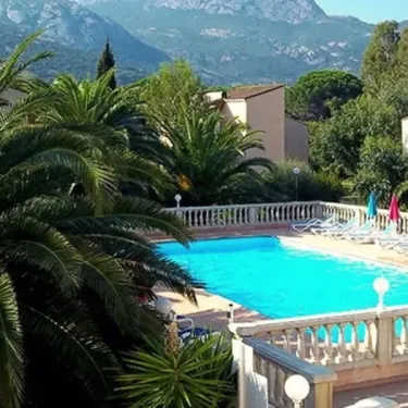 Piscine avec palmiers et montagnes en arrière-plan au Camping Résidence Thalassa