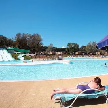 Personne se relaxant sous parasol au bord de la piscine au Camping Le Vorlen