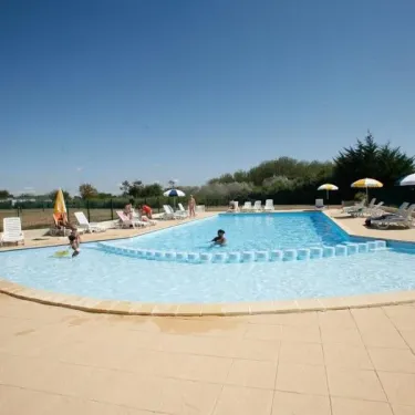 Piscine extérieure avec enfants nageant et chaises longues autour au Camping Saint Martin