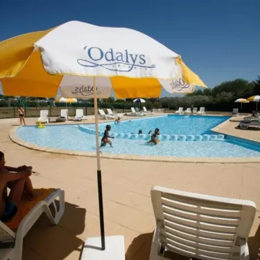 Enfants dans la piscine avec parasol Odalys et chaises longues autour du Camping Saint Martin