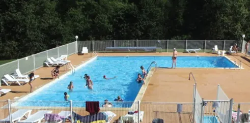 Personnes nageant dans la piscine entourée d'arbres au Camping Logis de Séchemailles