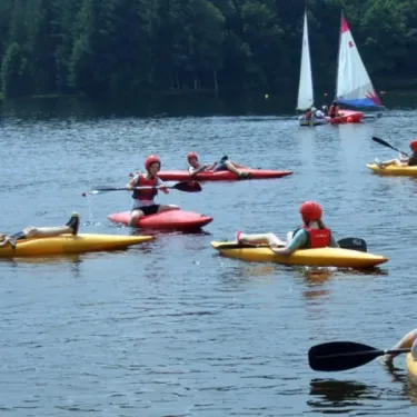 Personnes en kayak sur un lac, voilier à l'horizon, camping Logis de Séchemailles