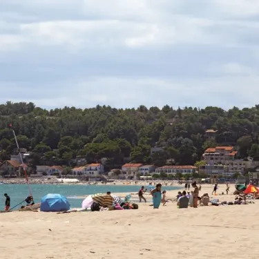 Plage animée avec des enfants, parasols et tentes près de l'eau
