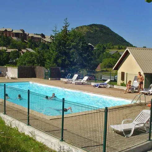Piscine extérieure avec des visiteurs et des chaises longues autour, près du Camping Les 4 Saisons