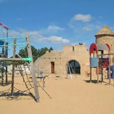 Parc infantile avec structures colorées et mur en pierre à Camping Acapulco