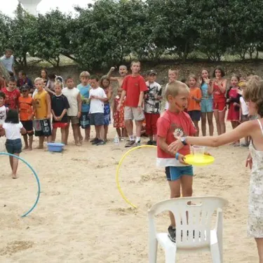 Enfants jouent au frisbee sur sable avec adultes à Camping Acapulco