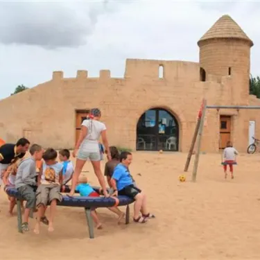 Camping Acapulco enfants sur trampoline près d'un château en sable