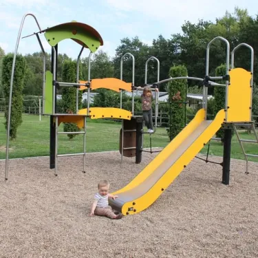 Enfants sur un parc de jeux avec toboggan jaune au Camping Les Acacias